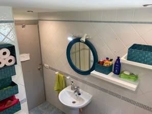 Ein Badezimmer mit Waschbecken, Spiegel und Ablagen für Pflegeprodukte.
