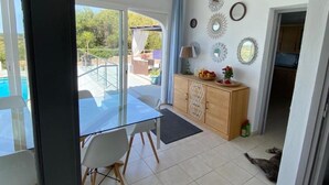 A spacious room with a glass door leading to an outdoor area, a wooden cabinet with decorative items, and a tiled floor. - Villa Marina, Relax, Piscina Privada, Barbacoa, Wifi (Son Vitamina)