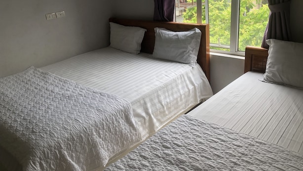 Un dormitorio con dos camas, una ventana con cortinas y vistas a la vegetación.