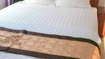 Un lit avec une tête de lit en bois, une literie blanche et une couverture marron.