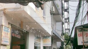 Un callejón estrecho con un hotel a la izquierda, un letrero de salón de belleza a la derecha y diversos letreros y cables colgando.