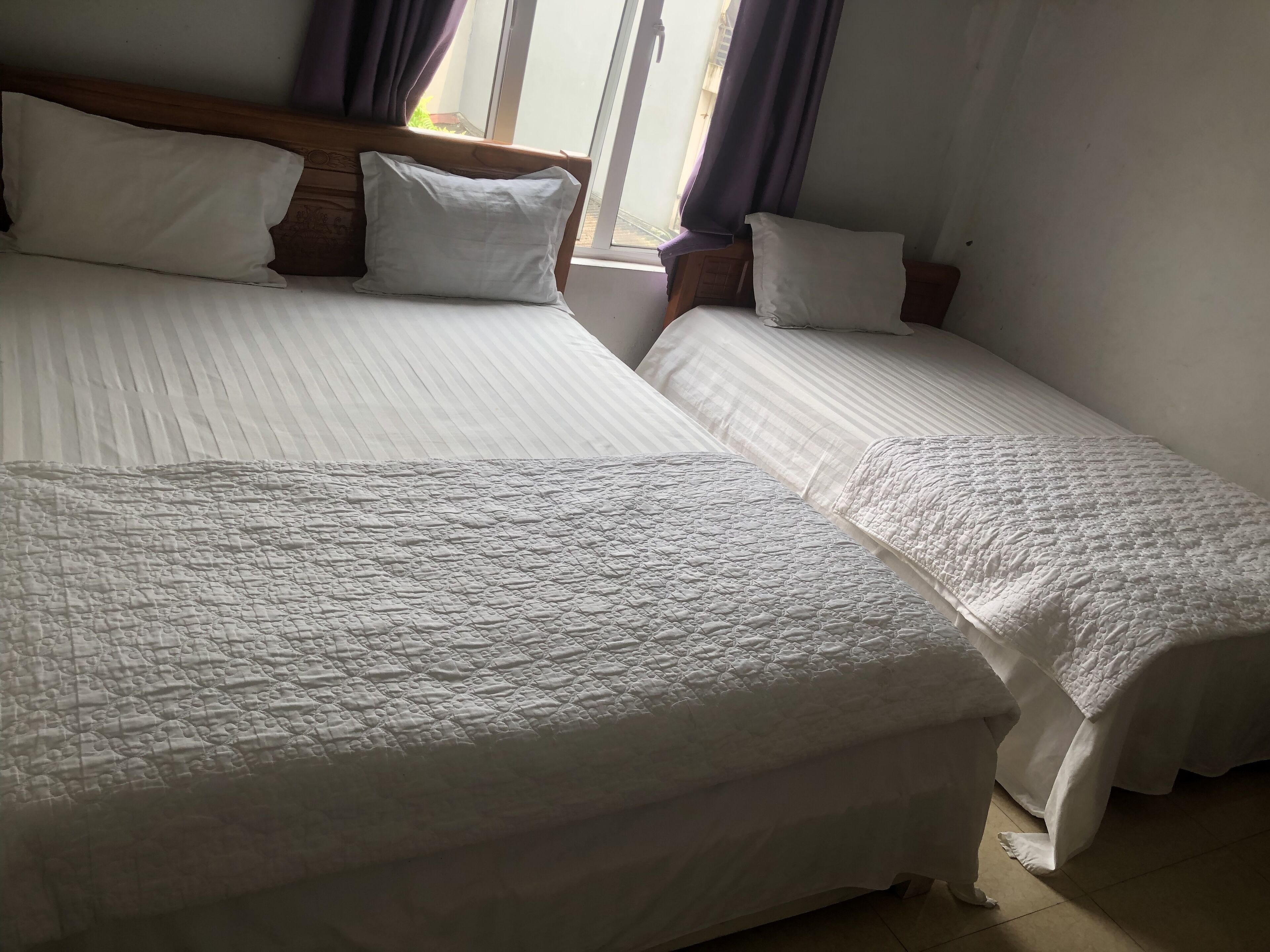 Une chambre avec deux lits, chacun doté de draps et d’oreillers blancs, et d’une tête de lit en bois.