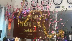 Un área de recepción con un escritorio de madera, un cartel que dice "LE TAN RECEPTION" y relojes que marcan la hora en Nueva York, Londres y Japón.