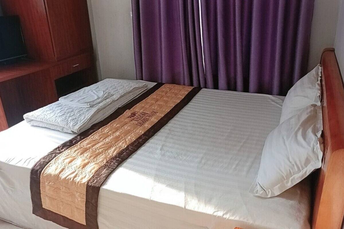 Una cama bien hecha con edredón blanco y una manta decorativa marrón.