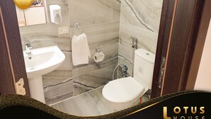 Ein Badezimmer mit Marmor-Spritzschutz, einem weißen Waschbecken, einer Toilette und einem Handtuchhalter.