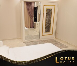 Quarto de hotel com cama, guarda-roupa, espelho e porta para uma casa de banho.