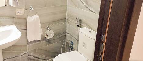 A bathroom with a marble backsplash, a white sink, a toilet, and a towel rack.