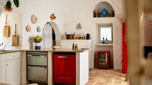 Eine kompakte Küche mit weißen Schränken, einem roten Kühlschrank und einem eingebauten Backofen.
