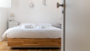 Ein ordentlich bezogenes Bett mit weißen Leinen und Handtüchern, ein Holzkopfbrett, ein Nachttisch mit Lampe und eine Wand mit Wandbildern von Mond und Sonne.