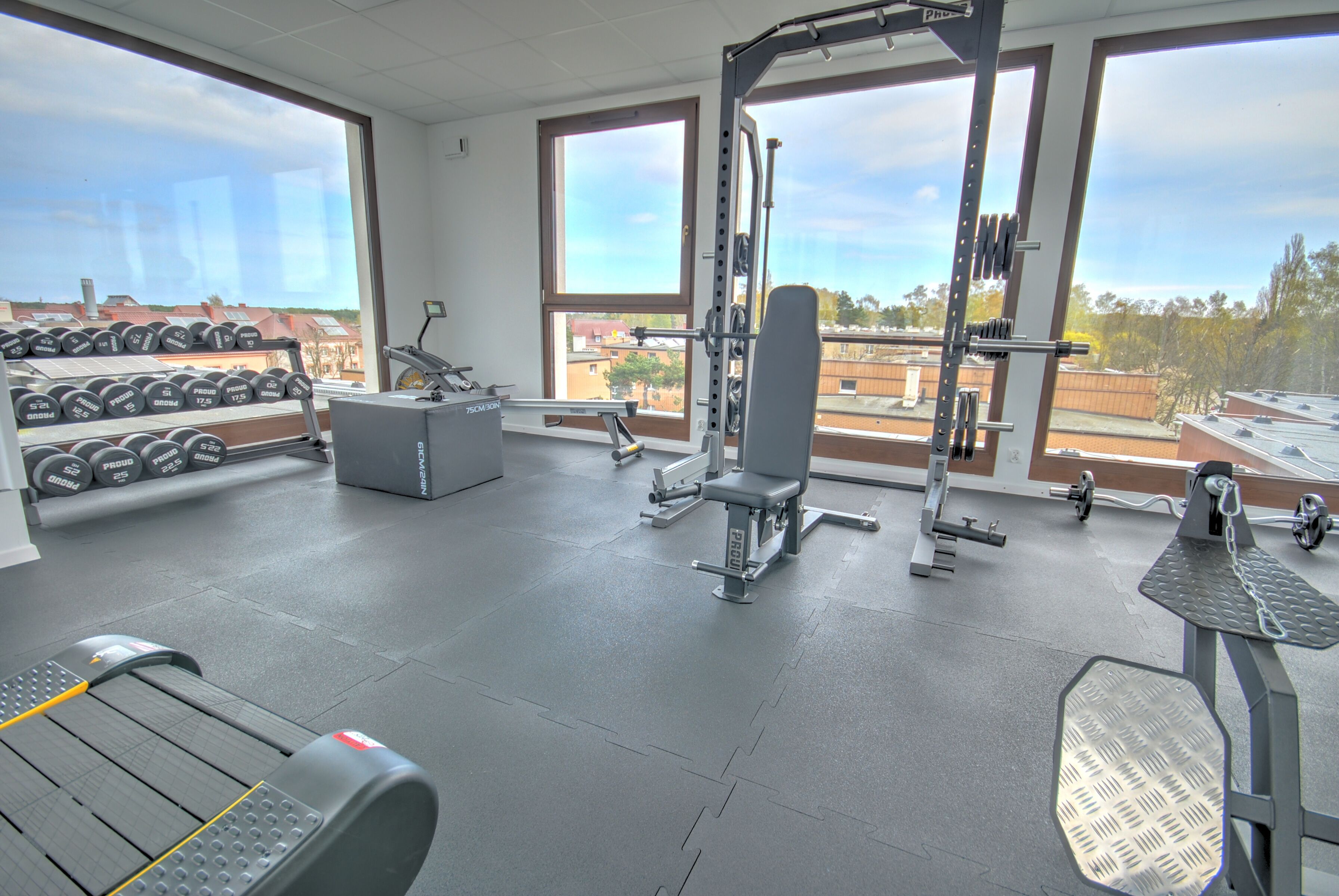 A gym with weightlifting equipment, dumbbells, and cardio machines.
