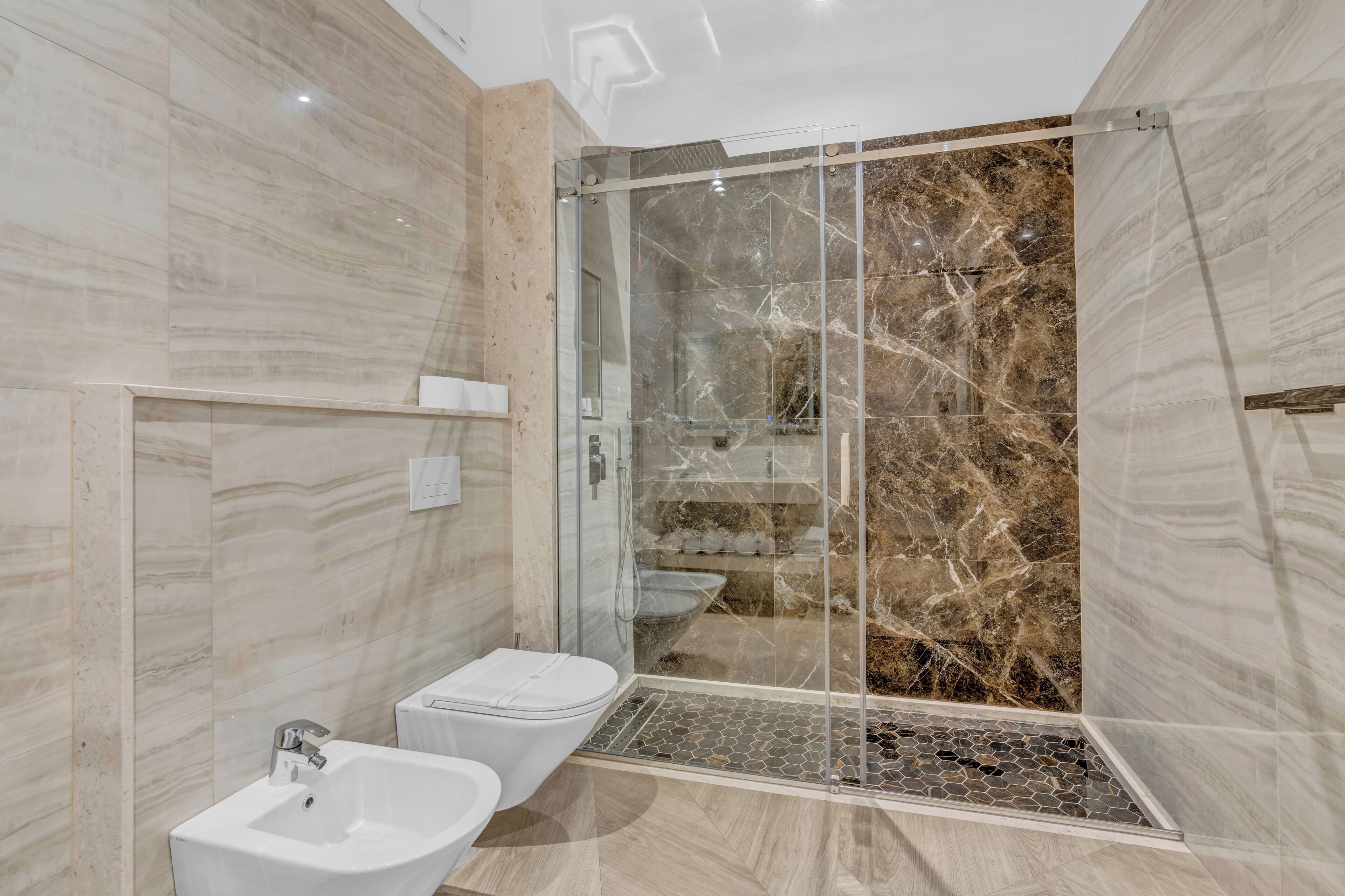 A modern bathroom with a glass-enclosed shower, a white sink, and a toilet.