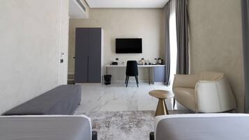 Ein modernes Hotelzimmer mit Bett, einer Couch, einem Schreibtisch mit Computer und einem an der Wand befestigten Fernseher.