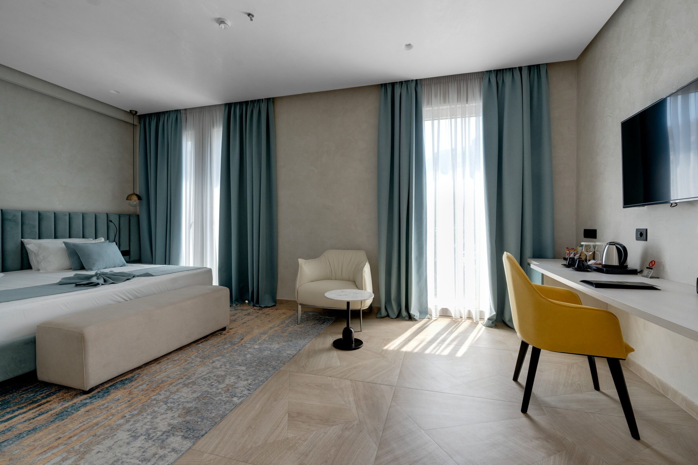 A modern hotel room with a bed, a sofa, a desk, and a chair.