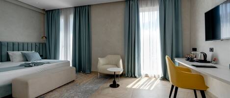 A modern hotel room with a bed, a sofa, a desk, and a chair.