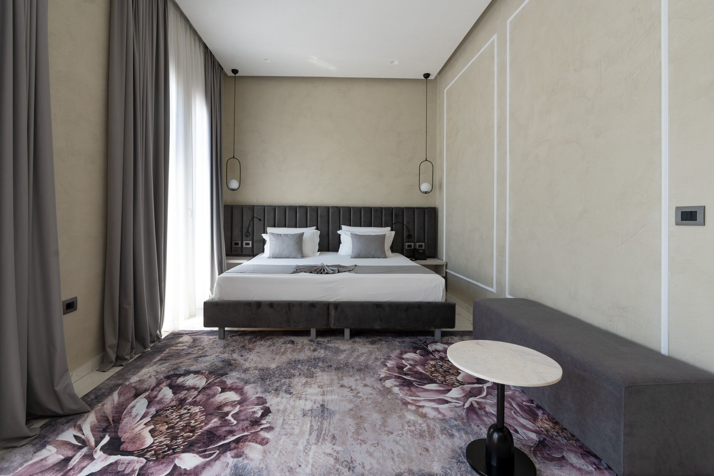 A modern hotel room with a large bed, a round table, and a sofa.