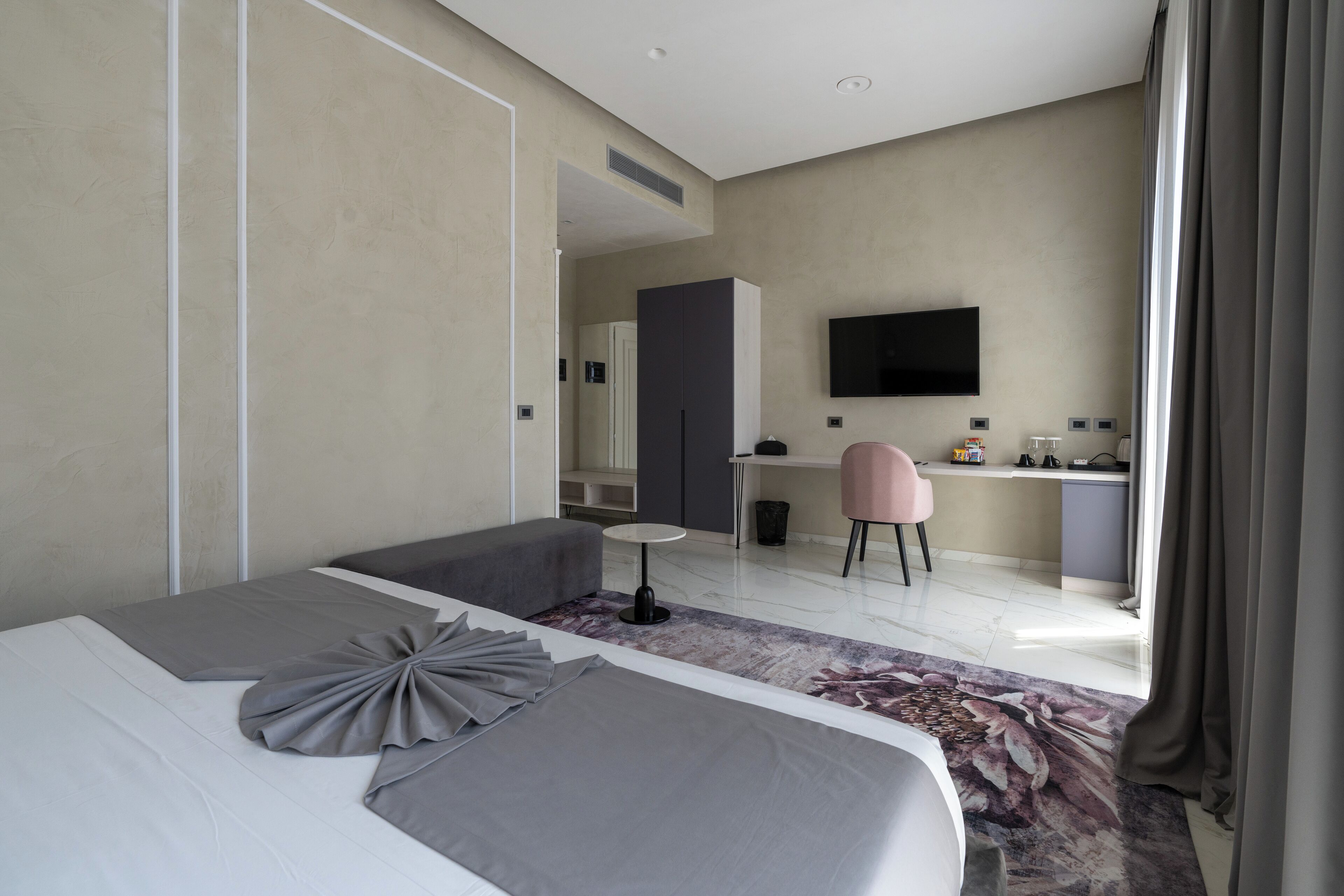 Ein modernes Hotelzimmer mit einem großen Bett, einem Schreibtisch, einem Sessel und einem Fernseher.