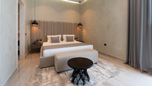 Ein modernes Schlafzimmer mit einem großen Bett, Nachttischen, einem runden Tisch und stimmungsvoller Beleuchtung.