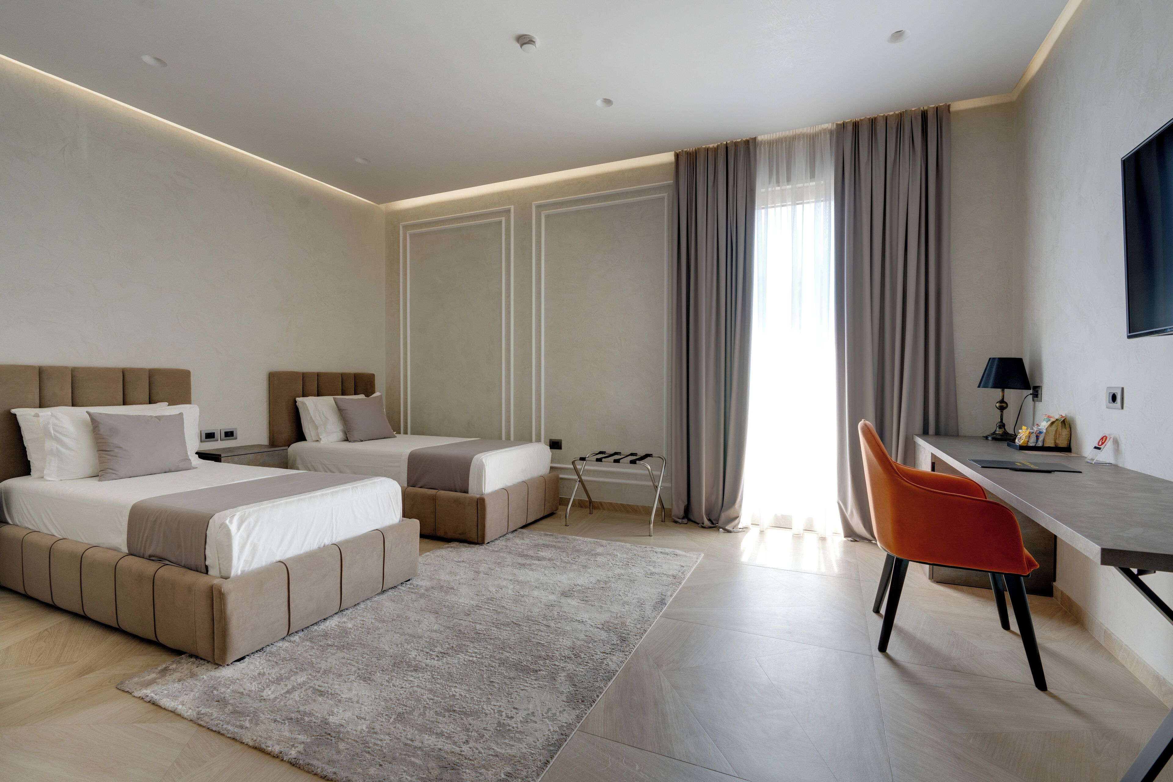 Una habitación de hotel moderna con dos camas, un escritorio y una silla.