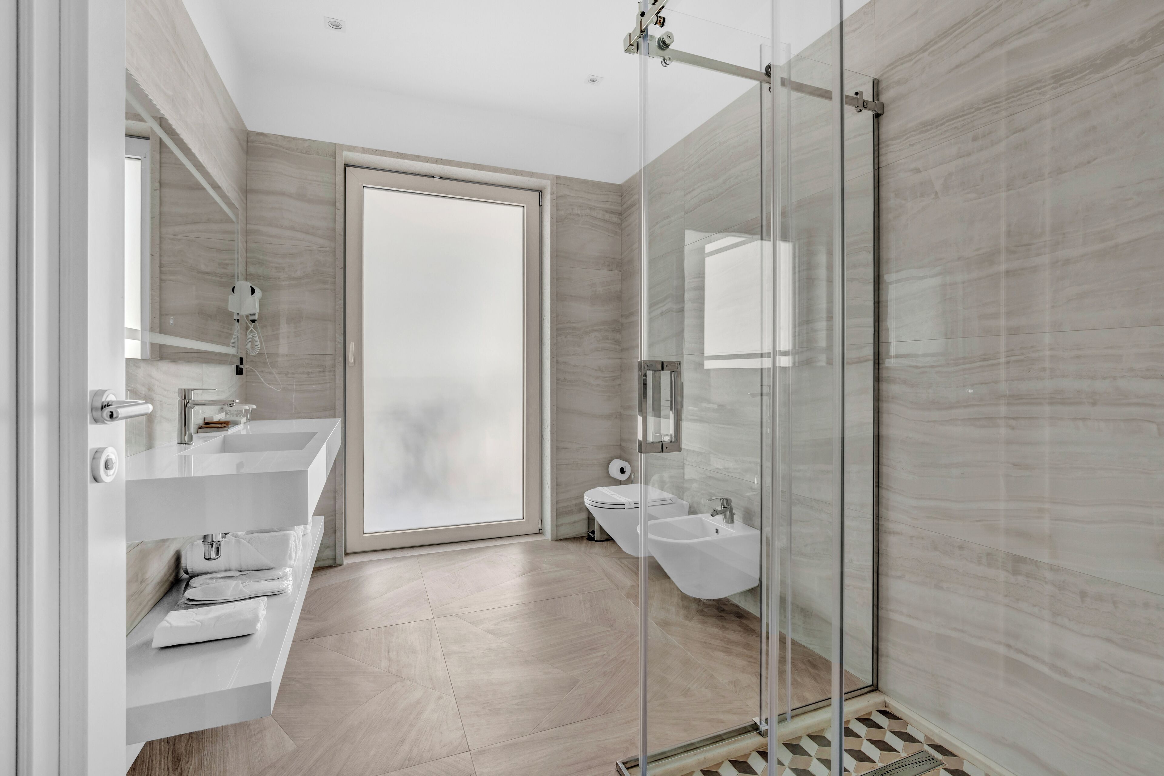 A modern bathroom with a glass shower enclosure, a large mirror, and a built-in sink.