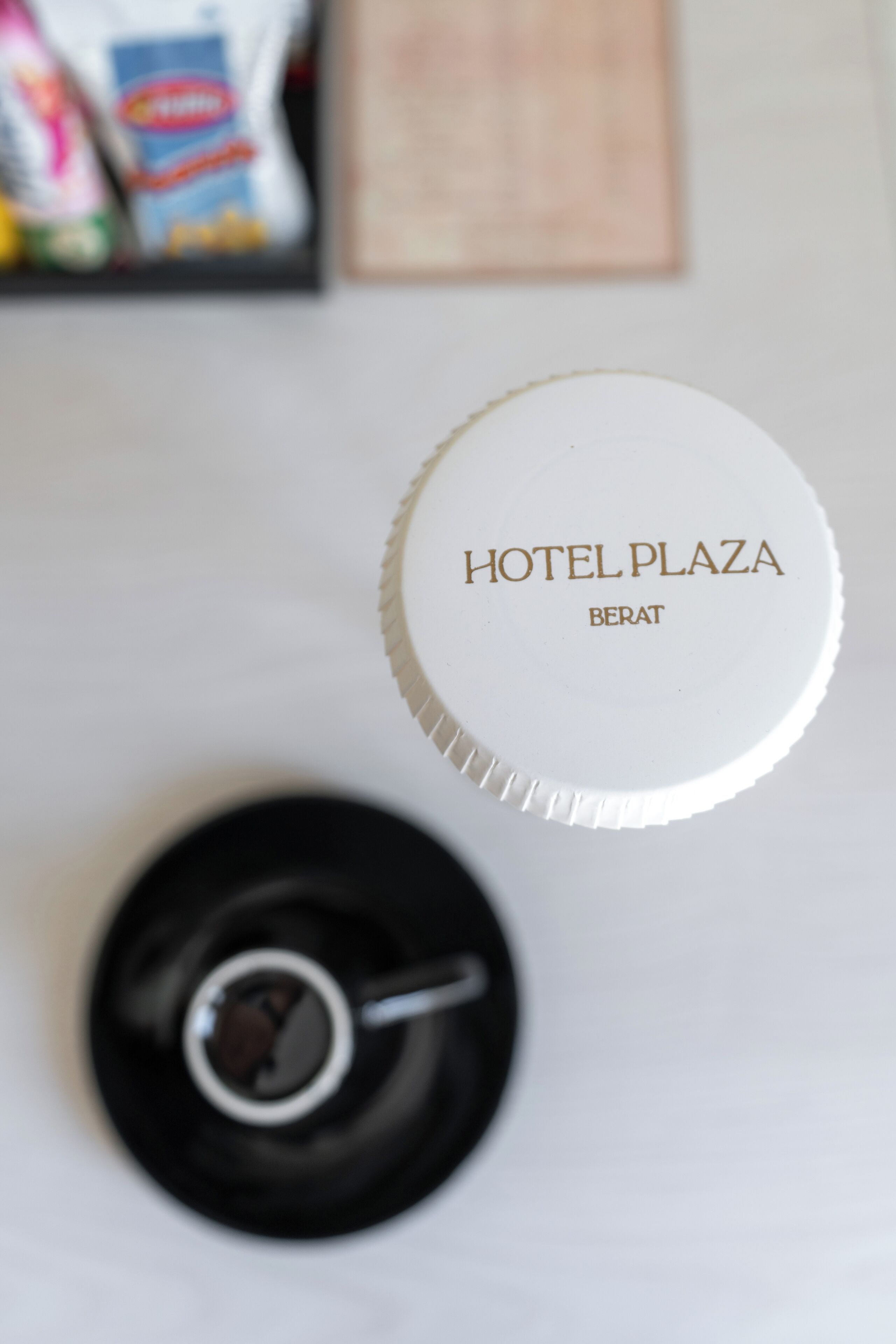 Een witte hotelkamer met een wit plafond, een zwarte plafondventilator en een witte muur met een lijstwerkfoto.