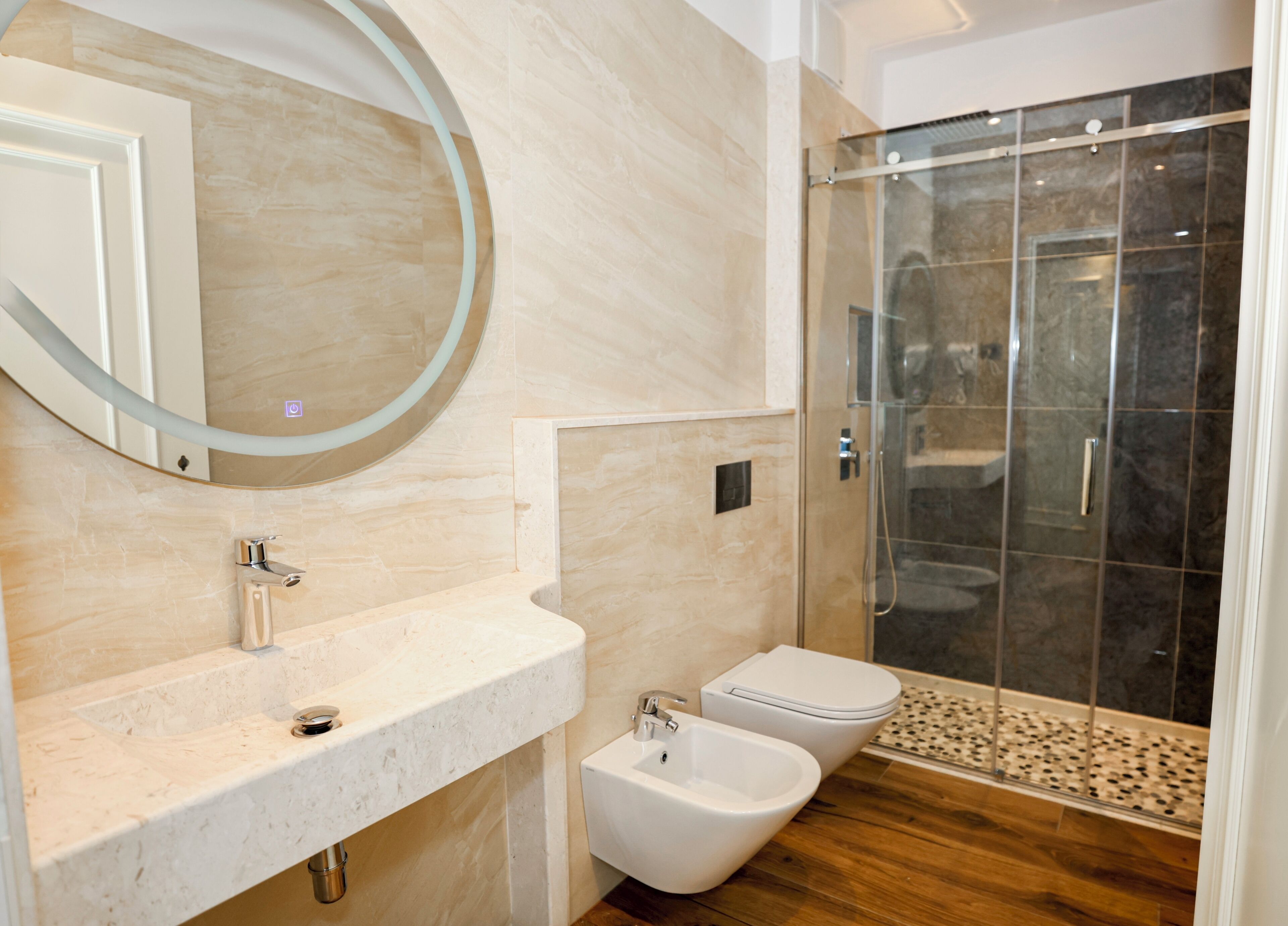 A modern bathroom with a marble vanity, a glass shower enclosure, and a bidet.