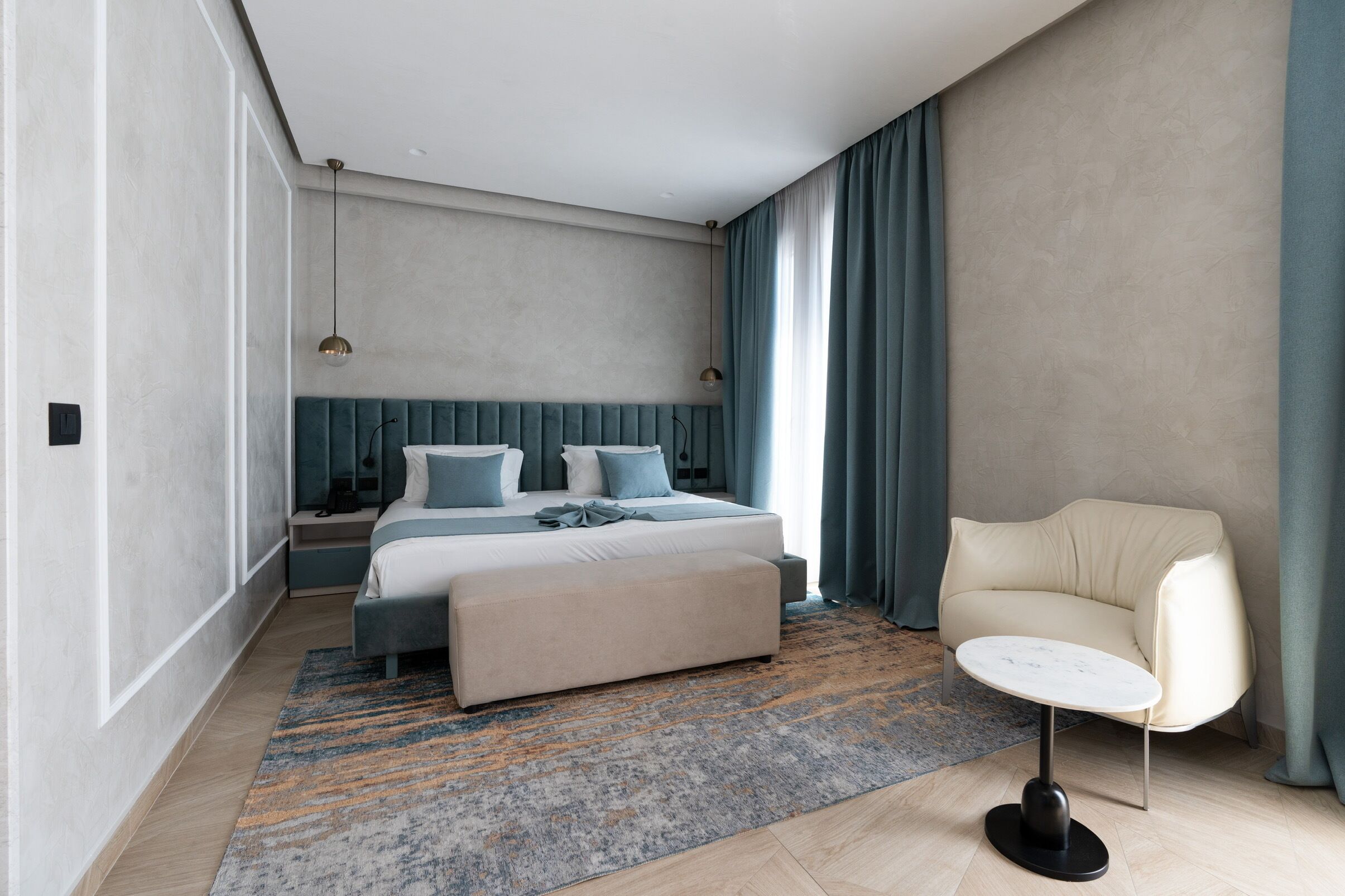 Een moderne slaapkamer met een bed, nachtkastjes, een stoel en een kleine tafel.
