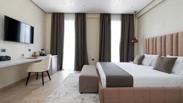 Une chambre d’hôtel moderne dotée d’un grand lit, d’un bureau avec une chaise, d’un téléviseur à écran plat et d’une grande fenêtre avec des rideaux.