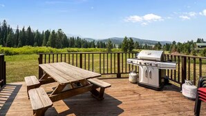 Eine Holzterrasse mit Picknicktisch und Grill.
