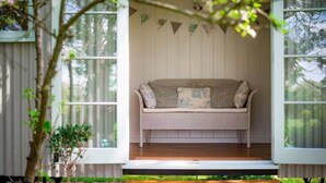 A cozy room with a bench, large windows, and a view of trees. - Beautiful Shepherds Hut B&B nr Stonehenge, Avebury, Salisbury, Bath - WiFi, TV (Haxton)