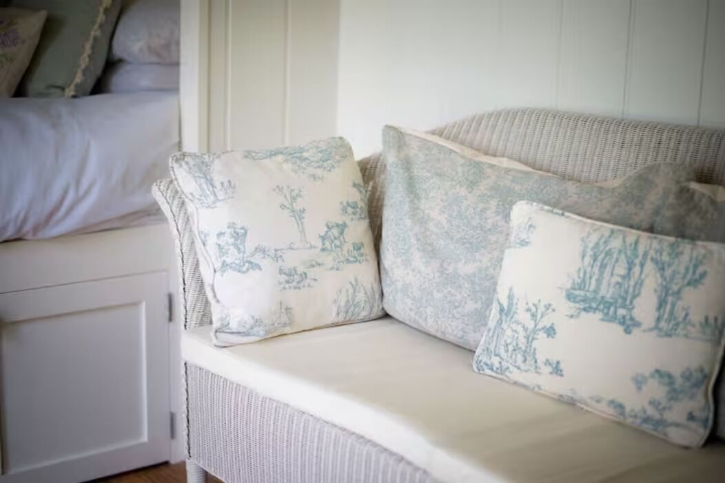 Un canapé en osier blanc agrémenté de coussins à motifs floraux.