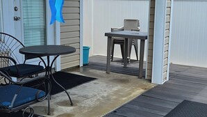 A covered patio with a table and chairs, a door, and a white fence. - Ground level condo near beach with a deck, washer/dryer AC & Pool (Corpus Christi)