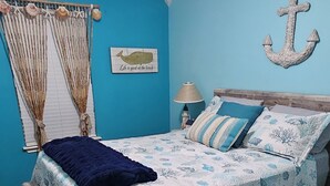 A bedroom with a bed, curtains, a wall anchor, a lamp, and a ceiling fan. - Ground level condo near beach with a deck, washer/dryer AC & Pool (Corpus Christi)