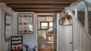 A cozy interior with a wooden staircase, a dining area with a view, and a wall with framed photos and a sign listing activities.