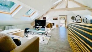 Tilava parvi- tai loft-tyyppinen asunto, jossa on korkeat katot, kattovalokuviot, suuri televisio ja ruokailutila.