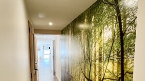 Käytävä, jossa on puulattia ja toisessa seinässä suuri metsäaiheinen seinämaalaus.