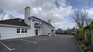 A two-story building with a parking lot, a balcony, and a garden with various plants. - Modern and Spacious No. 6 - sleeps 6 - free parking (Galway)