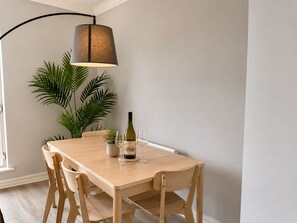 Ein Essbereich mit Tisch, Stühlen, einer Weinflasche und einer Lampe.