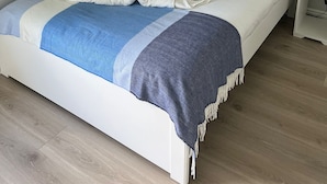 A neatly made bed with a blue and white blanket, two black pillows, and two white towels arranged in a heart shape. - Modern and Spacious No. 6 - sleeps 6 - free parking (Galway)