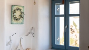 A room with a window, a wall-mounted painting, and decorative items including a ship and a bird.