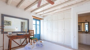 A room with a bed, a wooden desk, a chair, a mirror, and a wardrobe.