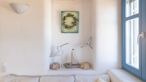 A cozy corner with a cushioned bench, a decorative wall piece, and a window with a view.