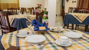 A dining area with checkered tablecloths, neatly set tables with plates, glasses, and a bottle of Lete. - Giardini di iside e osiride (Casamicciola Terme)