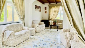 A cozy living room with patterned sofas, a coffee table, and a fireplace. - Giardini di iside e osiride (Casamicciola Terme)