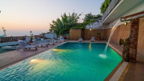 A swimming pool with lounge chairs, a brick wall, and a view of the sunset. - Giardini di iside e osiride (Casamicciola Terme)