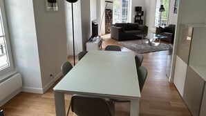A modern living space with a dining area, a sofa, a coffee table, and a bookshelf. - Like a House. Pleasant Duplex With Air-conditioned Bedrooms, Fully Equipped! (Boulogne-Billancourt)