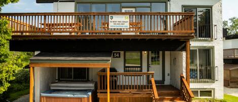 A two-story building with a balcony, a hot tub, and a sign indicating it is for rent.