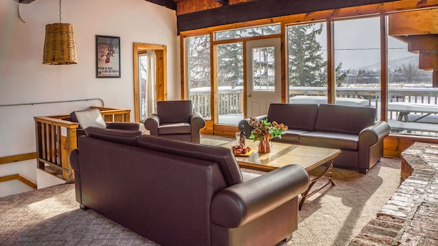 A cozy room with a wooden ceiling, large windows, a sofa, armchairs, and a coffee table. - Spacious 8 bdrm Blue Mountain Cottage, Perfect for Large Groups, Private Beach, BBQ, Hot Tub, Sauna (The Blue Mountains)