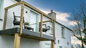 A two-story building with a balcony, a chimney, and a window with a green frame. - Ty Capel -  a dog that sleeps 8 guests  in 4 bedrooms (Pentraeth)