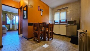 A compact kitchen with a dining table and chairs, a microwave, and a small refrigerator. - COMPLEJO RAICES PATAGONICAS DEPARTAMENTO 3 PERSONAS (Dina Huapi)