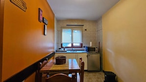 A compact kitchen with a dining area, a microwave, and a small refrigerator. - COMPLEJO RAICES PATAGONICAS DEPARTAMENTO 3 PERSONAS (Dina Huapi)